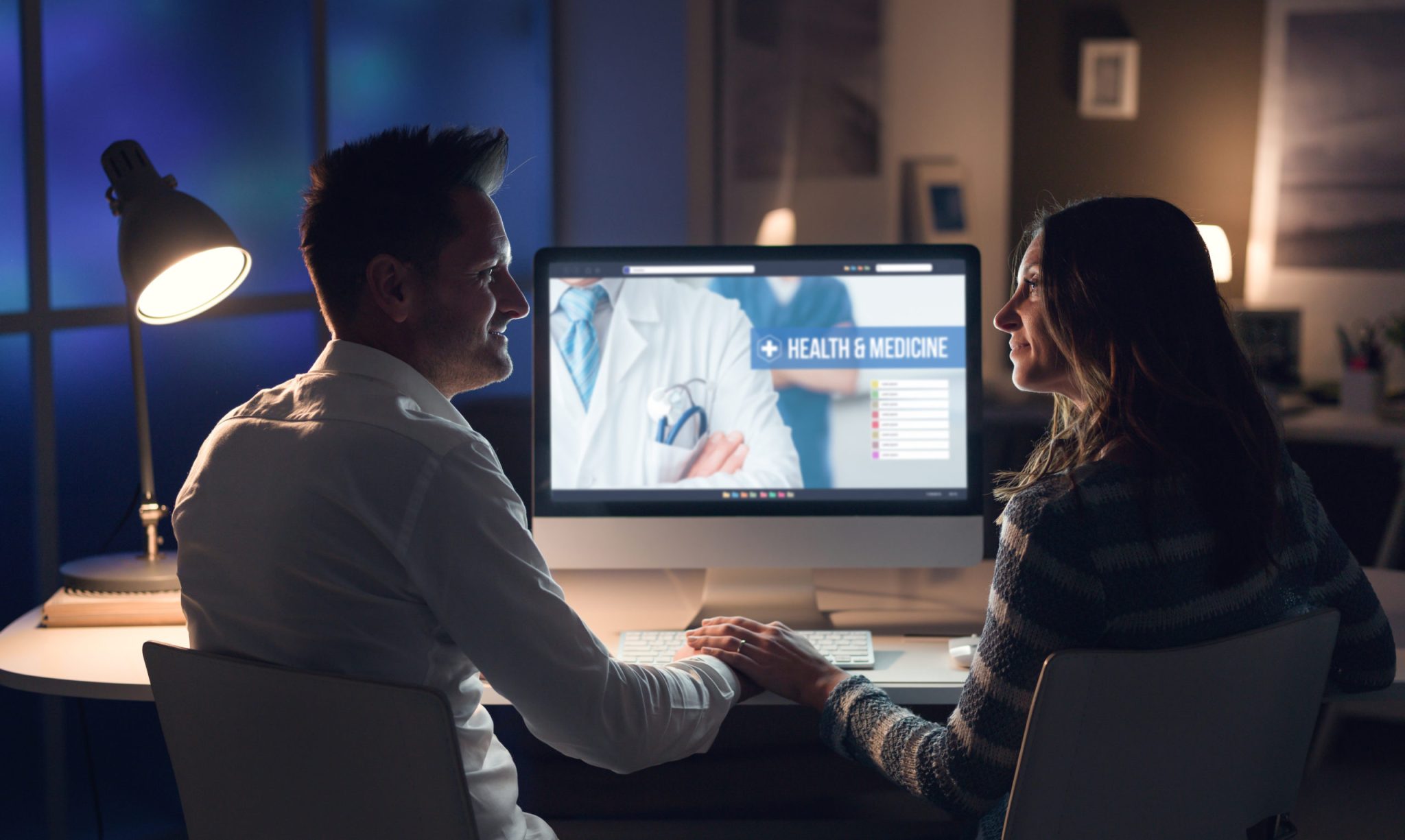 A couple reviewing health information together on a computer at night