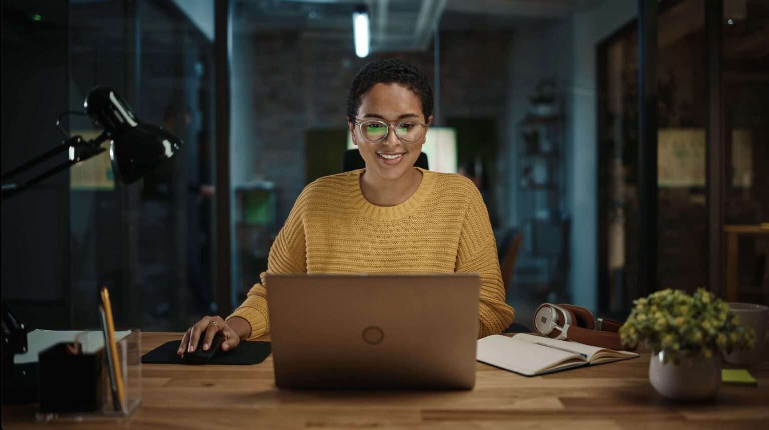 A smiling office worker typing on a laptop at a desk